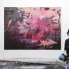Katja Gramann mit ihrem Acrylgemälde „Füreinander Nr. 4" im Atelier Künstlerin Katja Gramann kniet lächelnd vor ihrem großformatigen Acrylgemälde „Füreinander Nr. 4" in Beerentönen im Atelier