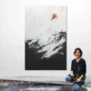 Künstlerin Katja Gramann kniet lächelnd vor ihrem großformatigen Gemälde „Neubeginn Nr. 5" im Atelier